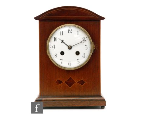 An Edwardian mahogany eight day strike mantle clock, Arabic numerals to a white enamelled dial below strung arch top pediment