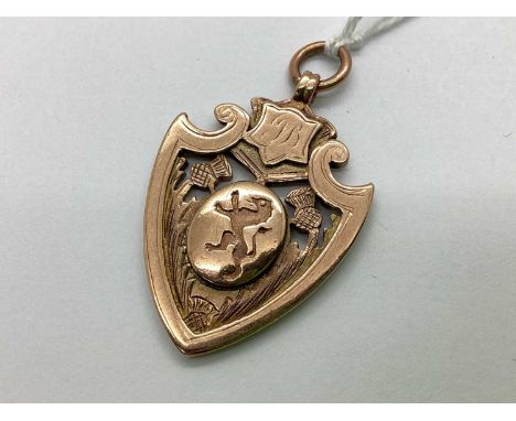A 9ct Gold Shield Medallion Fob, of pierced design baring Celtic thistle decoration and crested to centre oval panel, initial