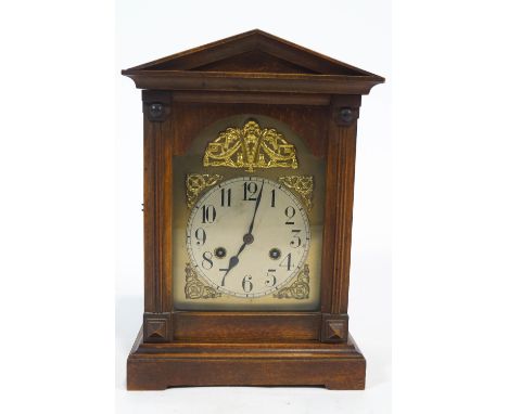 A 20th century mantel clock, with brass arched dial enclosed with a beech case, the eight day movement striking on a bell, 35