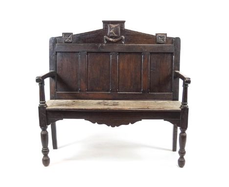 An oak hall bench with carved armorial on the cresting above a quadrupled panelled back and solid seat on turned legs, 111cm 