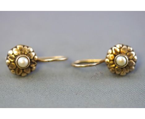 A yellow metal pair of earrings. Each centrally set with a seed pearl. Hook fittings. No hallmark - tests indicate sterling s