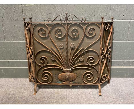 An early 20th century wrought iron fireguard decorated with central urn issuing flowers. 76cm High x 90cms wide x 17cms deep 