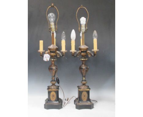 A pair of Empire style three branch lamps, with gilded detail over a black ground. The square section bases with paterae moti