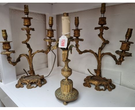 A pair of rococo style brass three branch candlesticks,&nbsp;height excluding fitting 33cm; together with another brass candl