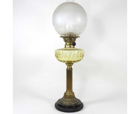 An early 20th century brass oil lamp, with a yellow glass font, 64cm highOverall dirty and tarnished. A faint split within th