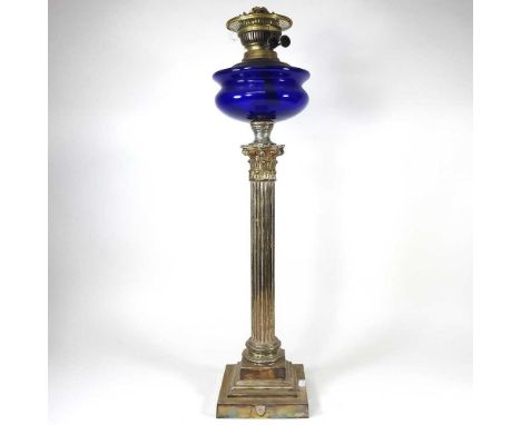 An early 20th century brass oil lamp, in the form of a Corinthian column, with a blue glass font, 70cm high