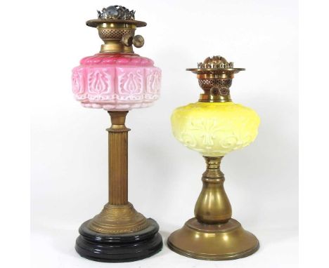 An early 20th century brass oil lamp, with a pink font, 47cm high, together with another with a yellow font, smaller (2)Both 