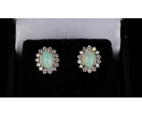 A pair of gold, opal and diamond oval cluster earstuds, each claw set with an oval opal within a surround of circular cut dia