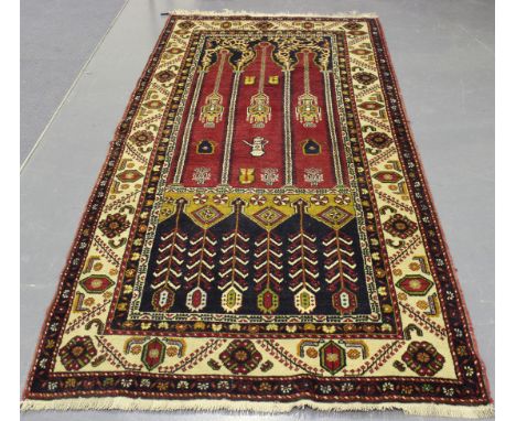 A Turkish prayer rug, mid-20th Century, the claret mihrab with stylized hanging lanterns and coffee pots flanked by architect