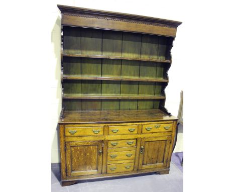 A George III provincial oak dresser, the moulded top above a shelf back, the base fitted with an arrangement of drawers and c