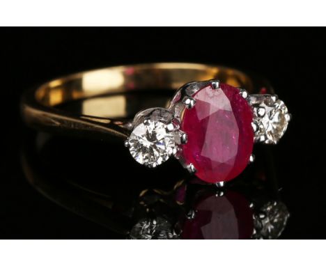 A gold, ruby and diamond three stone ring, claw set with the oval cut ruby between two circular cut diamonds, detailed '18ct'