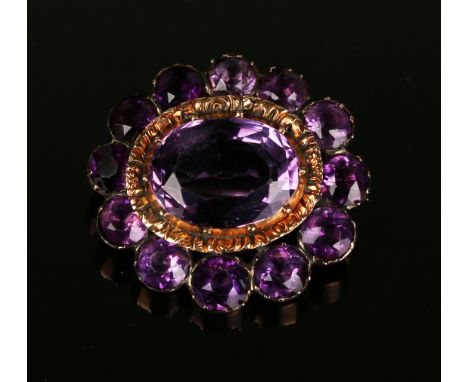 An early 19th Century amethyst set oval brooch, mounted with the principal oval cut amethyst within a surround of foil backed
