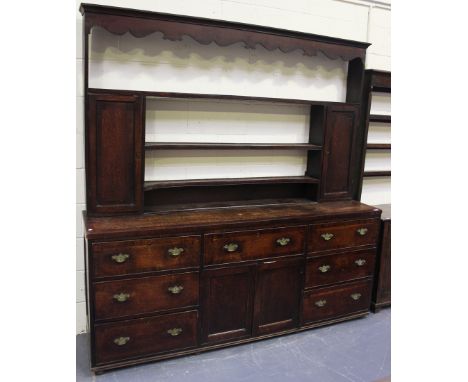 A late 18th/early 19th Century oak dresser, the shelf back with a shaped frieze and two panelled cupboards, the mahogany cros