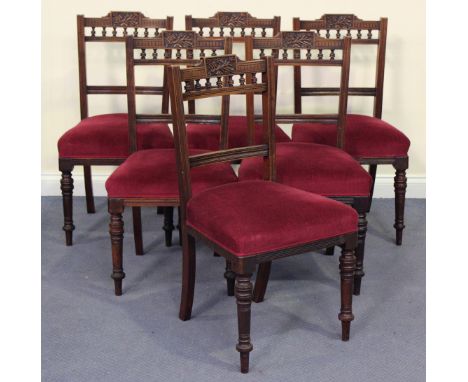A set of six Edwardian walnut dining chairs with carved top rails, the overstuffed seats upholstered in red velour, on ring t