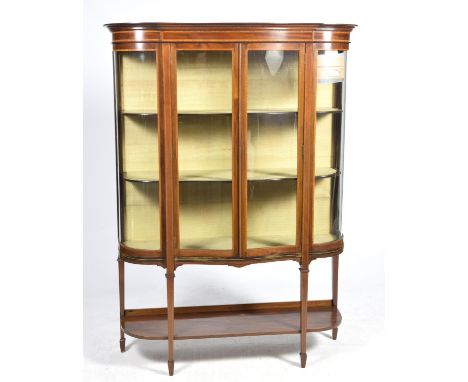 An impressive Edwardian serpentine mahogany display cabinet, originally supplied by Harrods,the cabinet with a moulded cornic