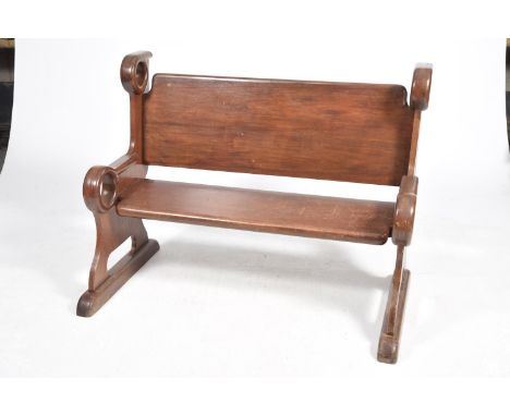 A Victorian mahogany pewThe board back embraced by shaped bracket supports with unusual ring terminals, 136x98x76cm. 