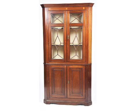 A George III mahogany freestanding corner cupboard Having a moulded cornice above a frieze inlaid with three satinwood fans o