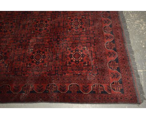 A large Bokhara carpet The rich claret ground with diamond shaped panels, with tasseled fringing, 360cm x 410cm. 