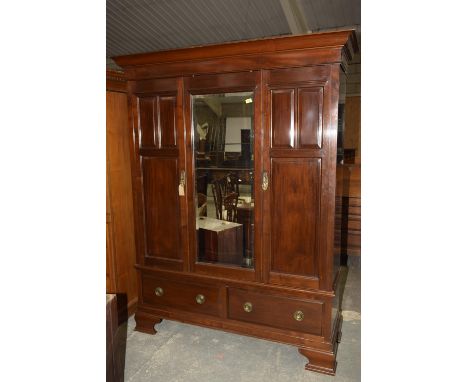 An early 20th century mahogany wardrobe, Having a cavetto cornice above a central mirrored door flanked by two paneled doors 