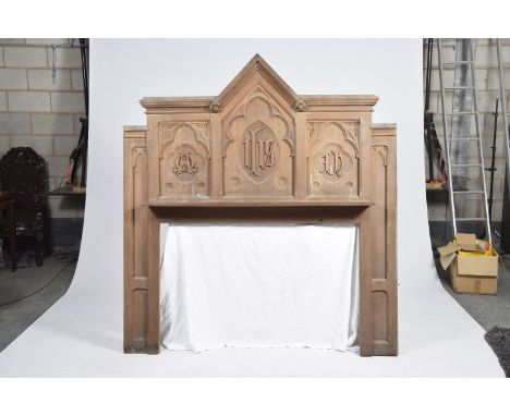 An unusual Victorian Gothic oak surround Having an architectural pediment above three panels each carved with lettering above