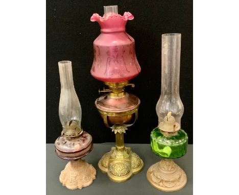 A Victorian copper and brass oil lamp, Eltex fittings, acid etched cranberry glass shade, 62.5cm high; others smaller  (3) 