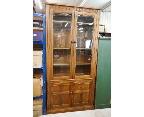 Ercol Golden Oak Display Cabinet, the upper section with two bevelled glazed doors opening to four adjustable shelves, over t