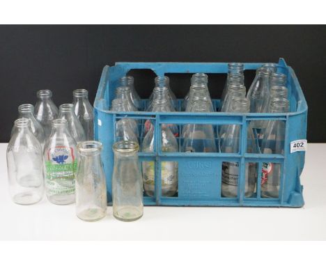 A collection of vintage advertising milk bottles within a plastic bottle crate. 