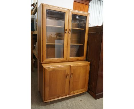 Ercol Light Elm Bookcase / Display Cabinet with two bevelled glazed doors opening to two adjustable shelves, over a cupboard 