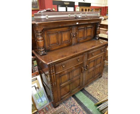 An oak court cupboard in the monastic taste, two panelled door cupboard flanked by turned columns to top, two short fluted fr