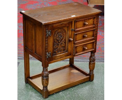 An Old Charm style small oak side cabinet, single door with carved panel beside three small drawers