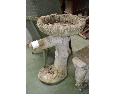Garden statuary- a bird bath support by a tree with flowers wrapped around the trunk
