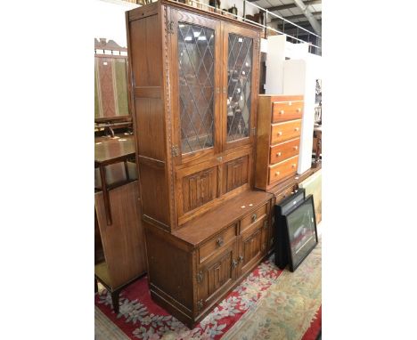 A Jaycee bookcase/cocktail cabinet, two lead glazed doors over linenfold panelled fall front to top, two short drawers over t