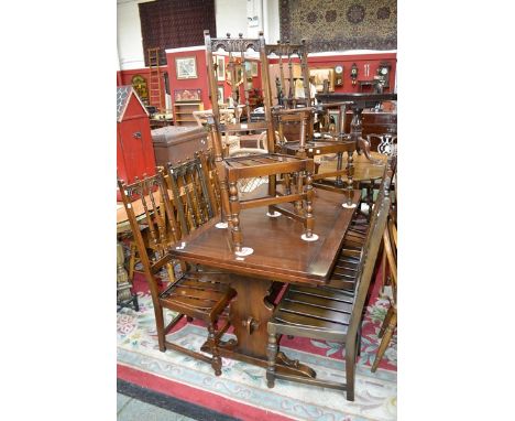 A dark oak Ercol drawleaf table, rectangular top, trestle style base; six spindle back dining chairs, two conforming carvers.