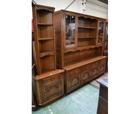 A Jaycee wall unit, shelving flanked by lead glazed cupboards to top, four short drawers over four carved and fielded panel d
