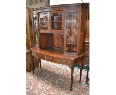 A Georgian style mahogany serpentine display cabinet, by Maple and Co., dentil frieze, two glazed door cupboard over recess f