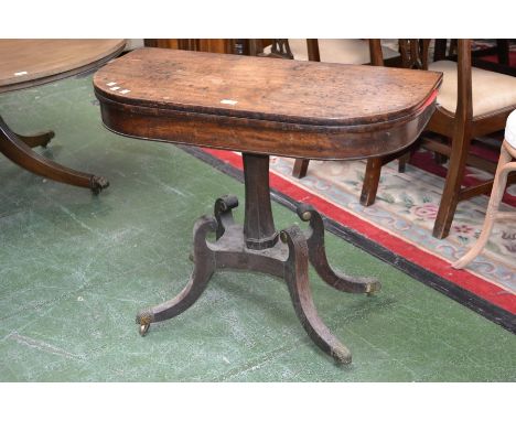 A Regency mahogany card table, foldover top enclosing red baize playing area, incurved octagonal column, quatrefoil socle, sc