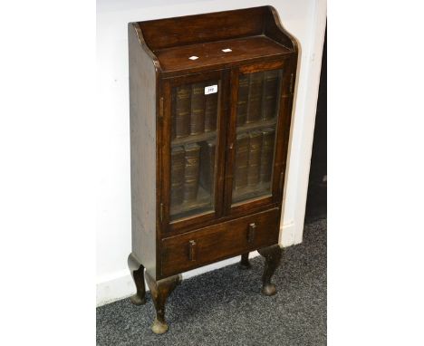 A small oak two door bookcase, base drawer, cabriole supports; Dickens novels.