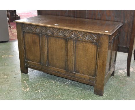 An oak blanket chest, plank top, three panel front with carved top rail, stile feet
