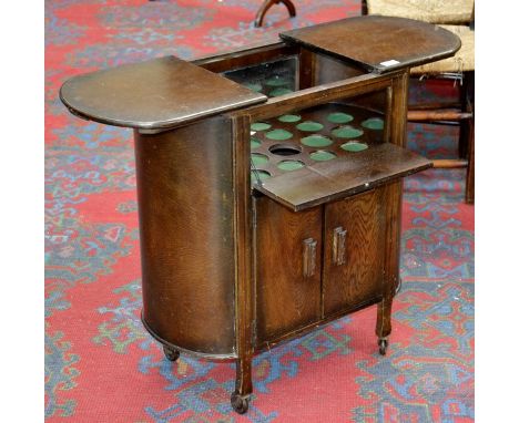A 1940's cocktail trolley of small proportion, obround two part sliding top, fall front over two door cupboard. 70cm high x 6