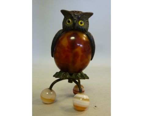 An early 20thC bronze finished and mottled brown celluloid novelty owl ornament, perched on a rotating tripod stand with cera