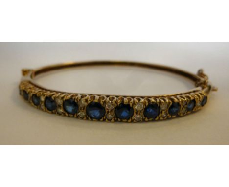 A 9ct gold hinged bangle, set with alternating, graduated sapphires and diamonds