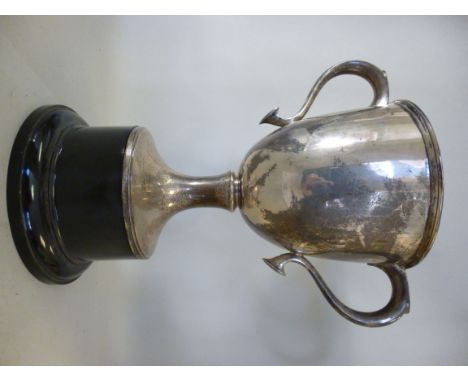 A silver trophy cup, having opposing, hollow, loop handles with shield shaped terminals and an applied wire rim, on a splayed