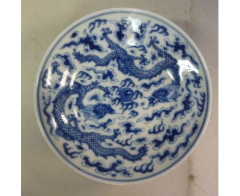 A late 19thC Chinese porcelain saucer dish, decorated in blue and white with dragons chasing The Sacred Pearl  bears a four c