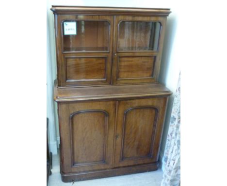 A late Victorian retailer's mahogany cabinet, the superstructure having a shelf top, over a pair of half glazed panelled door