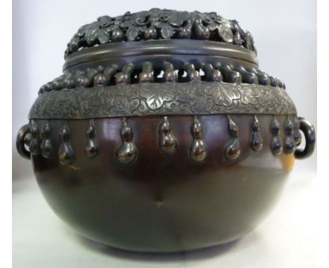 An early 20thC Japanese cast and patinated bronze koro of bulbous form, having a reticulated cover and opposing bail handles,