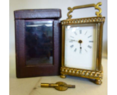 A 1920s lacquered brass cased carriage timepiece with cast kerb link chain ornament, bevelled glass panels and a folding top 
