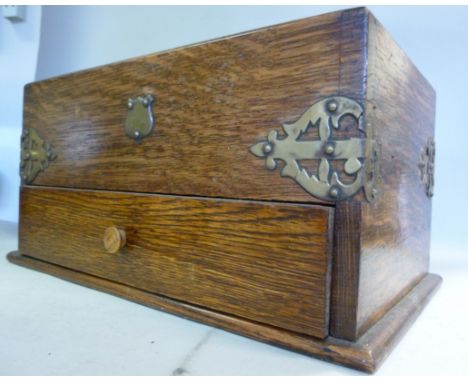 An early 20thC (unfitted) desktop, light oak cigar box with decoratively overlaid, pierced and rivetted brass corner mounts a