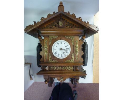 A late 19thC Austrian walnut cased Cuckoo clock with a dual pitched roof and carved ornament, decorated with applied brass mo