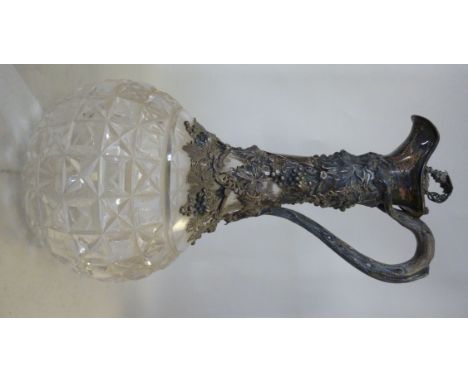 A late Victorian cut glass wine decanter of bulbous form, the long, narrow neck overlaid in silver, naturalistically cast wit