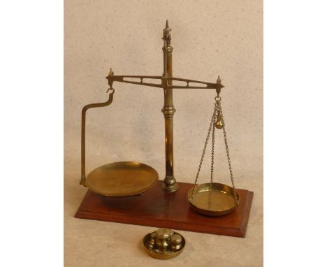 A large set of early 20th Century brass Scales together with various sized Weights, on a rectangular mahogany plinth style ba